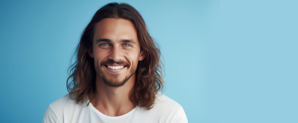 Wall Mural - Handsome elegant sexy smiling Caucasian man with perfect skin and long hair, on a light blue background, banner, close-up.