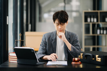 Attractive young lawyer in office Businessman and lawyers discussing contract papers laptop and tablet with brass scale on  desk in modern office. Law, legal services, advice,.