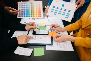  UX developer and ui designer brainstorming about mobile app interface wireframe design with customer breif and color code at modern office.