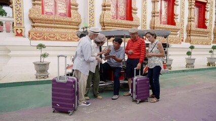 Wall Mural - Close-up, elderly Asian couple, elderly caucasian couple, are friends, drag large suitcase travel Chiang Mai together, inquiring about price tuk tuk for four people take around Chiang Mai.