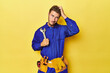 Technician in blue jumpsuit with tools on yellow being shocked, she has remembered important meeting.