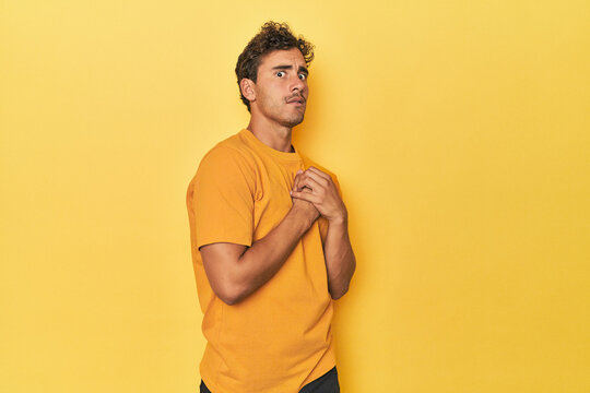 Young Latino man posing on yellow background scared and afraid.