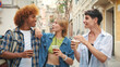 © Andrii Nekrasov - Group of happy friends, two guys and girl, walking with takeout drinks along city street, chatting and laughing