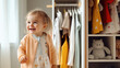 Cute little girl in children room on the background of closet with a lot of fashionable clothes. Fashion for children, modern comfortable child clothes store. 