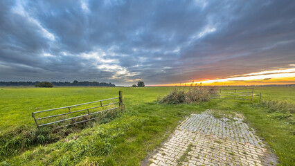 Canvas Print - Sunset over gate in lowland meadow