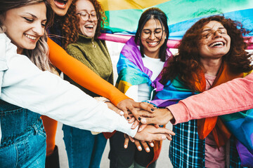 Wall Mural - Lgbt group of people stacking hands outside - Diverse happy friends hugging outdoors - Gay pride concept with crowd of guys and girls standing together on city street