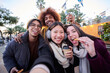 © CarlosBarquero - Selfie phone looking camera of cheerful friends eating chocolate churros street food stall at city outdoors. Generation z tourist group of happy people having fun in terrace cafeteria in winter time.