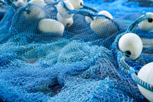 Pile Of Blue Fishing Net With White Floats. Trawler Fishing Net And Floats. Fishing Nets And Ropes. Tool For Catching Fish