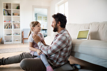 Young father playing and having fun with his daughter in the living room at home