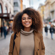 © Nayan - African cheerful young woman wearing glasses with curly hair standing on a city street looking at the camera on a blurred background