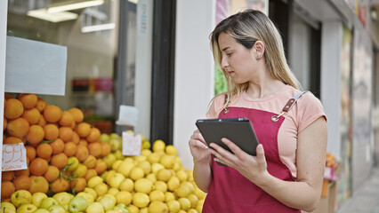 Canvas Print - Young blonde woman shop assistant using touchpad working at fruit store