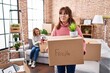 Mother and daughter moving to a new home holding cardboard box smiling looking to the side and staring away thinking.