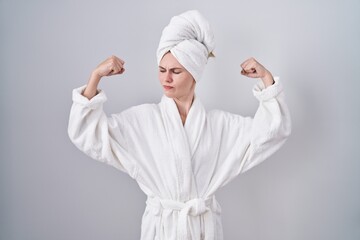 Wall Mural - Blonde caucasian woman wearing bathrobe showing arms muscles smiling proud. fitness concept.