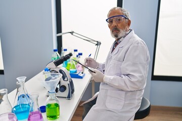 Poster - Senior grey-haired man scientist writing report working at laboratory