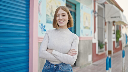 Poster - Young blonde woman standing with crossed arms at street