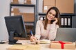 © Krakenimages.com - Young beautiful hispanic woman ecommerce business worker talking on smartphone writing on notebook at office