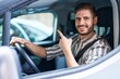 © Krakenimages.com - Hispanic man with beard driving car smiling happy pointing with hand and finger to the side