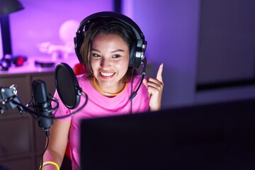 Sticker - Hispanic young woman playing video games smiling with an idea or question pointing finger with happy face, number one