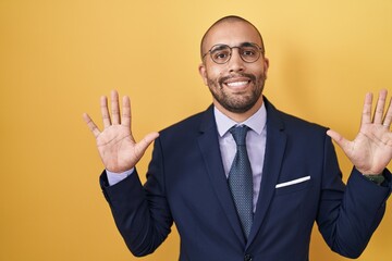 Wall Mural - Hispanic man with beard wearing suit and tie showing and pointing up with fingers number ten while smiling confident and happy.