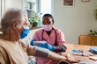 © Marko Geber - Young female caregiver measuring the blood pressure of her senior patient at their home