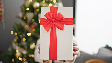 Poster - Young beautiful hispanic woman holding christmas gift over face at home