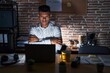 © Krakenimages.com - Young hispanic man working at the office at night skeptic and nervous, disapproving expression on face with crossed arms. negative person.
