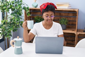 Poster - African american woman using laptop and drinking coffee sitting on table at home