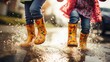 Close-up of children's feet jumping over puddles in rubber boots.