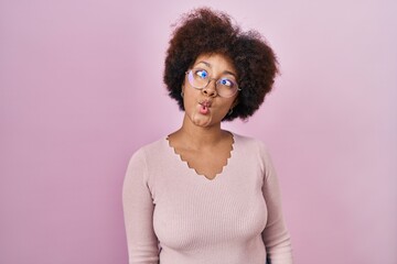 Wall Mural - Young african american woman standing over pink background making fish face with lips, crazy and comical gesture. funny expression.