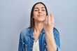 Hispanic woman standing over blue background doing italian gesture with hand and fingers confident expression