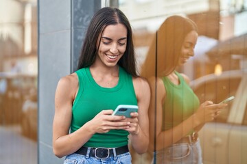 Wall Mural - Young beautiful hispanic woman smiling confident using smartphone at street