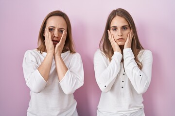 Poster - Middle age mother and young daughter standing over pink background tired hands covering face, depression and sadness, upset and irritated for problem