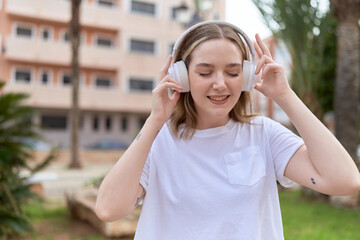 Poster - Young caucasian woman listening to music at park