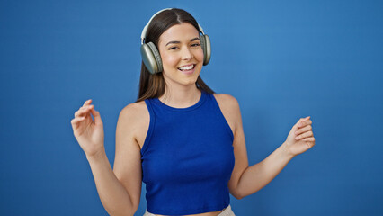 Poster - Young beautiful hispanic woman listening to music and dancing over isolated blue background