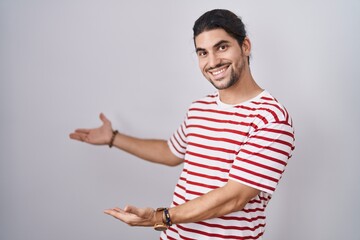 Sticker - Hispanic man with long hair standing over isolated background inviting to enter smiling natural with open hand