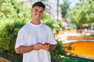 Sticker - Young hispanic man smiling confident using smartphone at park