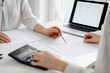 © rogerphoto - Accountant using a calculator and laptop computer for counting taxes with a client or a colleague at white desk in office. Teamwork in business audit and finance