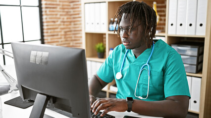 African american man doctor using computer working at the clinic