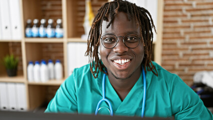 Sticker - African american man doctor using computer smiling at the clinic