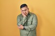 © Krakenimages.com - Hispanic young man standing over yellow background thinking looking tired and bored with depression problems with crossed arms.