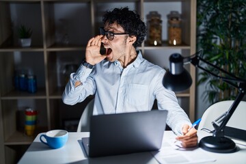 Canvas Print - Hispanic man working at the office at night shouting and screaming loud to side with hand on mouth. communication concept.