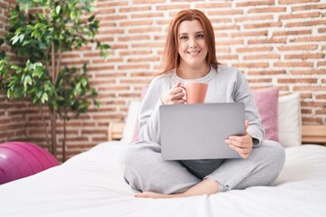 Wall Mural - Young beautiful plus size woman using laptop drinking coffee at bedroom