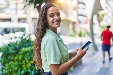 Wall Mural - Young beautiful hispanic woman smiling confident using smartphone at street