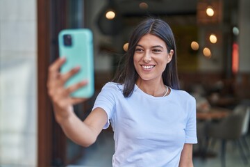 Canvas Print - Young beautiful hispanic woman smiling confident making selfie by the smartphone at street