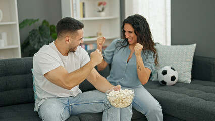 Sticker - Man and woman couple watching soccer game celebrating at home