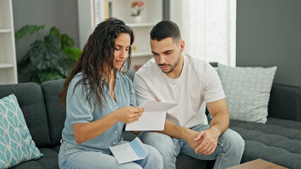 Sticker - Man and woman couple reading document sitting on sofa at home