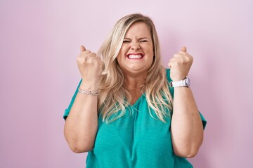 Poster - Caucasian plus size woman standing over pink background excited for success with arms raised and eyes closed celebrating victory smiling. winner concept.