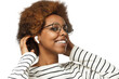 © Damir Khabirov - Smiling african american woman wearing glasses, touching her afro hair, listening to music via wireless earphones