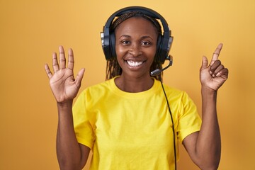 Wall Mural - African american woman listening to music using headphones showing and pointing up with fingers number seven while smiling confident and happy.