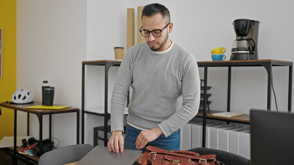 Wall Mural - Hispanic man business worker putting laptop in briefcase at office